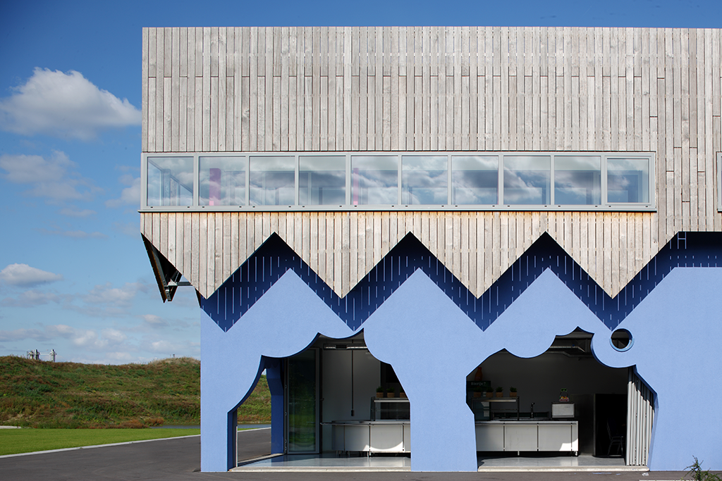 Le bâtiment abrite une salle polyvalente, des bureaux et un café. Ce « hangar décoré» est revêtu d’une enveloppe figurative en bois dont la découpe évoque le passé industriel du site. © Rob Parrish